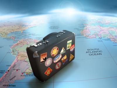 imagem mostra  uma mala de viagem e um mapa-mundi