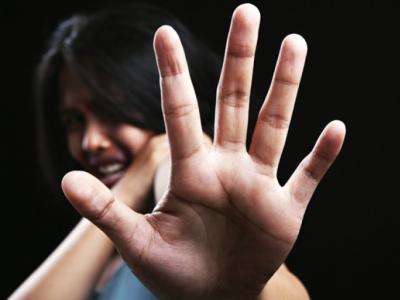 Imagem mostra uma mulher assustada esticando a mão para se defender