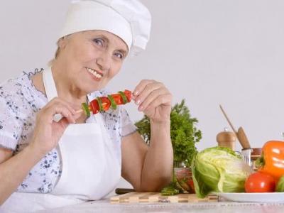 Imagem mostra idosa comendo um espetinho de frutas 