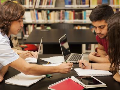 Imagem mostra pessoas estudando em uma mesa