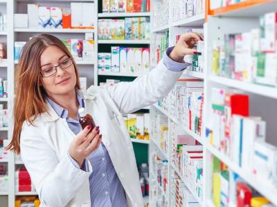 Imagem mostra uma mulher pegando remédios em uma prateleira