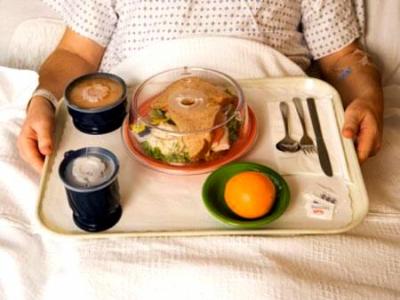 Imagem mostra uma pessoa comendo em uma cama de hospital