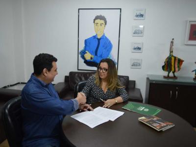 Imagem mostra locutor e vice-reitora firmando parceria 