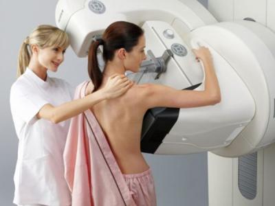 A imagem mostra uma mulher realizando o exame de mamografia