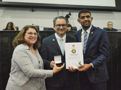 Imagem mostra deputados entregando prêmio para representante da UNAMA