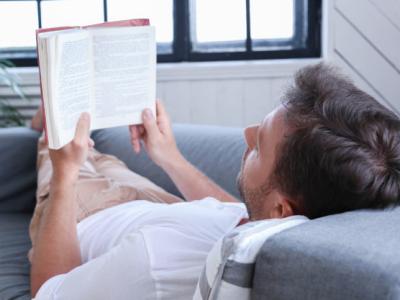 Imagem mostra homem lendo no sofá