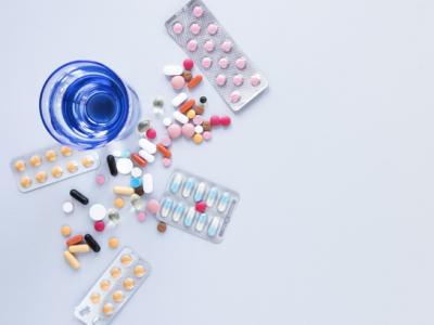 Imagem mostra remédios e copo azul em cima da mesa